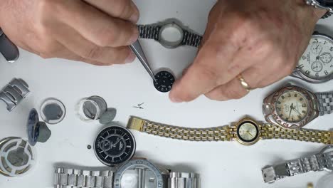 overhead-shot-showing-the-hands-of-a-caucasian-man-fixing-watches-on-a-table-full-of-watch-parts