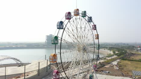 rajkot-atal-lake-drone-view-phone-camera-is-moving-towards-the-side,-there-is-a-big-giant-wheel-and-many-gardens-are-visible-on-the-side,-Rajkot-New-Race-Course,-Atal-Sarovar