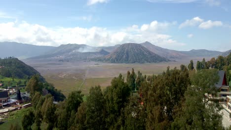 Capture-the-serene-beauty-of-village-life-nestled-in-the-foothills-of-Mount-Bromo,-as-the-majestic-mountain-provides-a-breathtaking-backdrop,-aerial-4k-drone-footage