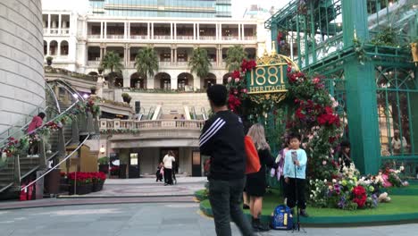 Rising-shot-showing-tourists-take-enjoying-the-famous-1881-Heritage-in-Tsim-Sha-Tsui,-Kowloon,-Hong-Kong