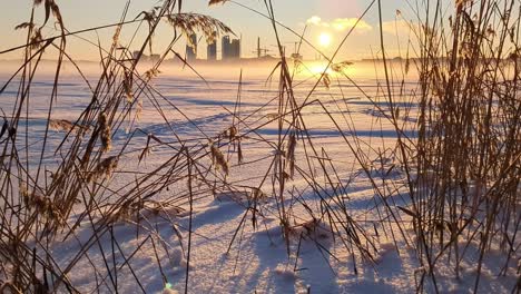 Sunset-in-winter-landscape,-frozen-sea-and-city-skyline,-rising-shot