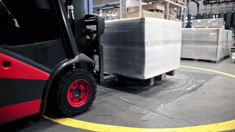 Logistics-employee-drive-a-forklift-containing-stacked-cargo-boxes-or-packages-and-slowly-pickup-box-on-the-floor
