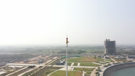 rajkot-atal-lake-drone-view-camera-moving-towards-the-side-there-is-a-big-garden-behind-it-and-many-buildings-around,-Rajkot-New-Race-Course,-Atal-Sarovar