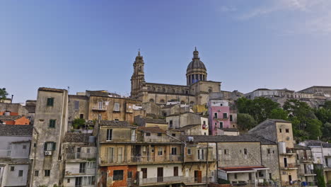 Ragusa-Italy-Aerial-v7-drone-fly-around-the-hill,-tracking-shot-along-the-residential-townhouses-capturing-charming-Ibla-town-and-hilltop-Duomo-di-San-Giorgio---Shot-with-Mavic-3-Cine---June-2023