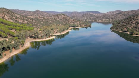 Picturesque-aerial-view-of-Sierra-de-Andujar-nature-reserve-and-Encinarejo-reservoir-blue-waters