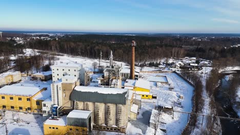 Aerial-view-of-an-industrial-building-with-forest-background-in-winter,-Silute,-Lithuania