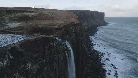 Kilt-rock-and-mealt-falls-in-scotland-with-snow-patches,-cliffside-and-sea,-aerial-view