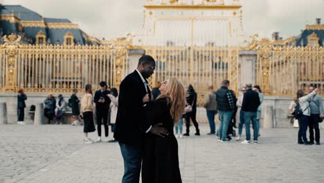 Mixed-race-couple-cuddling-and-flirting-in-front-of-the-famous-Castle-Versailles-golden-main-gate-of-honor---cinematic-slomowtion