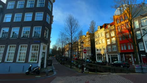 Leere-Amsterdamer-Straße-Mit-Kanal-Und-Häusern-Im-Winter-Mit-Sonnenlicht
