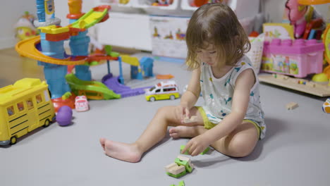 Una-Niña-Pequeña-Rubia-Construye-Una-Torre-De-Bloques-En-La-Sala-De-Estar-De-Su-Casa-Sentada-En-Una-Alfombra-Gris---Cámara-Lenta