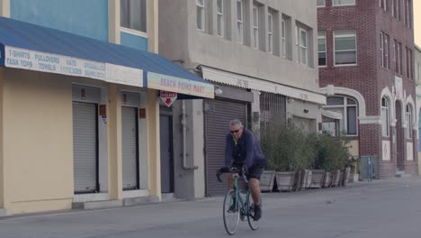 Middle-aged-white-male-riding-a-bicycle-in-Venice-Beach,-California-in-slow-motion