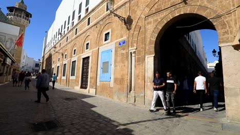 Tunisians-pedestrians-walk-cobblestone-street-with-arched-entranceway