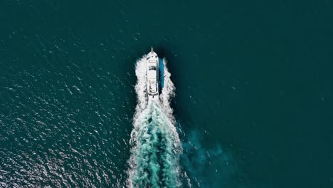 Overhead-view-of-motorboat-moving-at-high-speed-while-leaving-white-wake-trail-on-blue-sea-surface