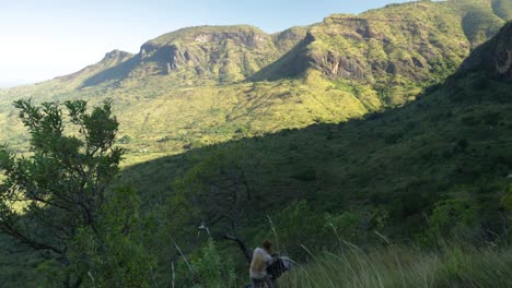 Ein-Wanderer-Zieht-Einen-Rucksack-An,-Während-Er-Die-Atemberaubende-Aussicht-Auf-Einen-Tropischen-Vulkan-In-Ostafrika-Genießt