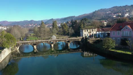 Calm-water-in-River-Vez-reflects-symmetrical-arches-under-bridge-in-town-of-Arcos-de-Valdevez-in-Portugal