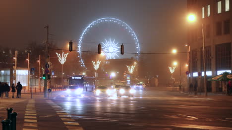 Budapest-Eye---Ferris-Wheel-With-Traffic-At-Andrassy-Avenue-At-Night-In-Budapest,-Hungary