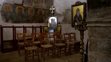Interior-De-Una-Antigua-Iglesia-Pequeña-Con-Hagiografías-Murales-E-Imágenes-De-Santos,-Toma-Cinematográfica-De-Mal-Humor