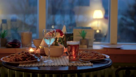 Cozy-dinner-setting-with-spaghetti-and-drinks-on-a-table,-warm-indoor-lighting,-evening-vibe