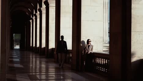 Ein-Mann-In-Einem-Karierten-Anzug-Und-Mit-Weißen-Hosen-Geht-Zu-Den-Frauen-In-Den-Bögen-Der-Königlichen-Residenz-Im-Louvre-In-Paris,-Sonniger-Tag,-Der-Ein-Dating-Paar-Mit-Sonnenbrille-Und-Modernem-Lebensstil-Darstellt