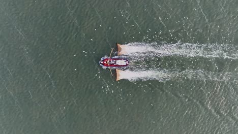 Drohnenaufnahme-Von-Oben-Eines-Fischerboots,-Das-Die-Netze-Durch-Das-Wasser-Zieht