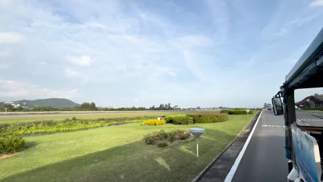 Transport-Mit-Offener-Tür-Entlang-Des-Flughafens-Der-Insel-Koh-Samui-An-Einem-Sonnigen-Tag,-Blick-Von-Der-Linken-Tür-Des-Fahrzeugs