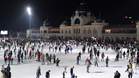 Large-crowd-of-people-ice-skating-at-popular-City-Park-Ice-Rink,-Budapest,-wide