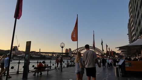 Abendliche-Menschenmassen-Im-Hafen-Von-Sydney-Mit-Blick-Auf-Die-Berühmte-Brücke,-Warmes-Licht-Bei-Sonnenuntergang