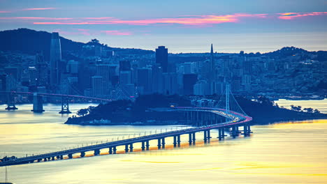 San-Francisco-Bay-Bridge-Bei-Sonnenuntergang-–-Skyline-Der-Stadt-Von-Oakland,-Kalifornien-Aus-Gesehen,-Zeitraffer