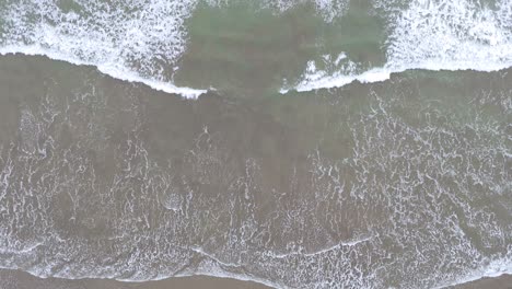 Overhead-aerial-view-of-ocean-waves-rolling-onto-shore