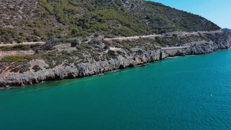 Cercanias-panoramic-train-passing-along-and-on-cliffs-of-Garraf-coast,-Spain