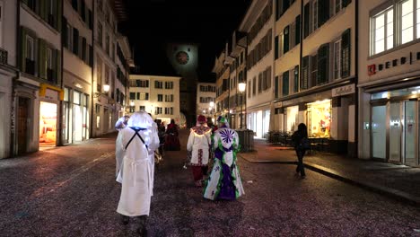 Gente-Vestida-De-Fantasma-Blanco-Caminando-Por-La-Calle-Suiza-Por-La-Noche-Durante-El-Carnaval