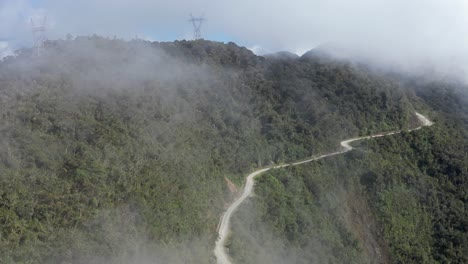 Gravel-road-cut-high-into-steep-cloudy-jungle-mountain-side-in-Bolivia