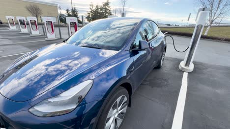 Blaues-Elektrofahrzeug-Wird-An-Einem-Tesla-Supercharger-Aufgeladen