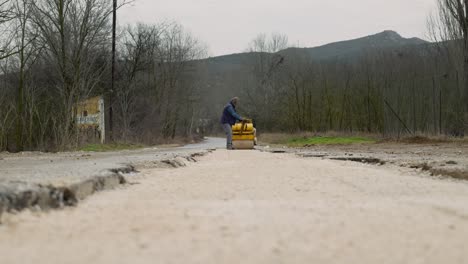 Männlicher-Arbeiter-Mittleren-Alters-Bedient-Doppeltrommel-Straßenwalze-Mit-Vibrationskompaktkies