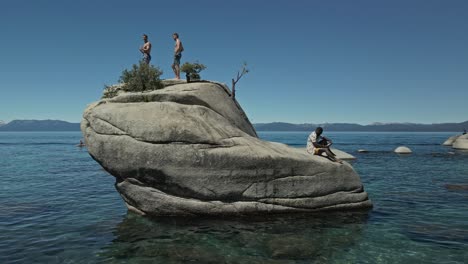Aerial-shot-of-three-guys-on-a-rock-in-Lake-Tahoe