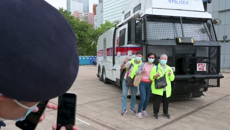 Un-Oficial-De-Policía-Les-Toma-Una-Foto-A-Sus-Partidarios-Mientras-Posan-Con-Un-Vehículo-De-Cañón-De-Agua-De-La-Policía-Durante-El-Día-De-Educación-Sobre-Seguridad-Nacional-En-La-Escuela-De-Policía-De-Hong-Kong-En-Hong-Kong,-China.