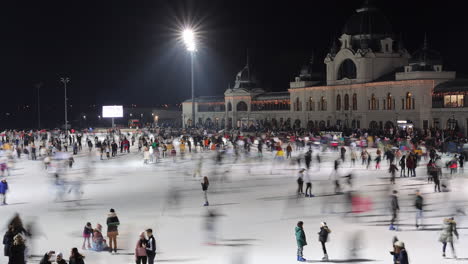 Timelapse-De-Personas-Patinando-Por-La-Noche-En-La-Pista-De-Hielo-Del-Parque-De-La-Ciudad,-Budapest,-Gran-Angular