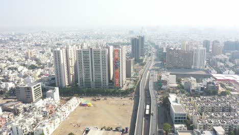 Vista-Aérea-De-Drones-De-Rajkot-Que-Va-Hacia-El-Lado-Donde-Pasan-Muchos-Vehículos-Por-Un-Gran-Puente-Alrededor