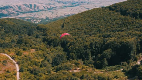 Luftaufnahme-Eines-Gleitschirms,-Der-über-Einem-Wald-Fliegt