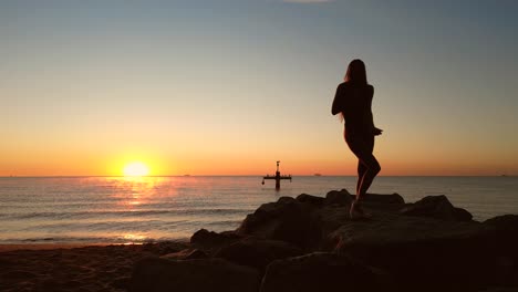 Mujer-Sexy-Acrobática-Practicando-Baile-De-Yoga-En-La-Playa-Al-Amanecer.