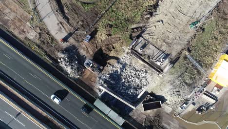 Drone-shot-of-rubble-from-a-construction-site-next-of-a-highway-where-cars-and-trucks-are-driving