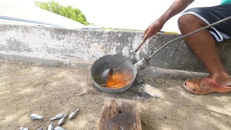 Mann-Gießt-Geschmolzenes-Blei-In-Eine-Form-Im-Freien-Mit-Schöpfkelle,-Traditioneller-Metallbearbeitungsprozess,-Sonniger-Tag