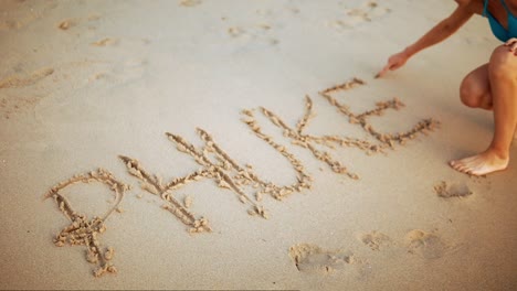 A-Female-Tourist-Writing-PHUKET-In-The-Sand