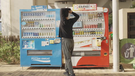 Person-contemplating-drink-selection-from-urban-vending-machines,-beverage-choices-in-Hong-Kong-street