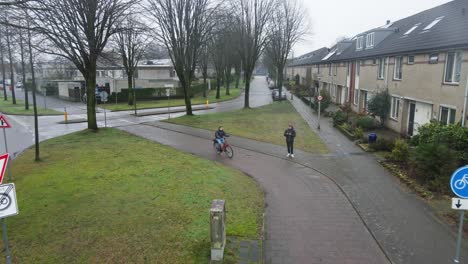 Aerial-of-a-cyclist-bicycling-through-a-suburban-neighborhood-on-a-rainy-day-in-the-Netherlands