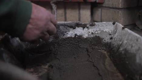 Close-up-of-hands-applying-cement-on-bricks-during-construction-work