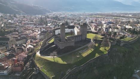 Bellinzona,-Suiza,-Increíble-Castillo-Retroiluminado-En-La-Cima-De-Una-Colina-Acercándose-Al-Vuelo