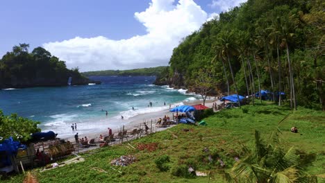 Low-Aerial-view-of-sunbathing-and-swimming-Tourists-in-Crystal-Bay-beach-in-Nusa-Penida---BALI,-Indonesia