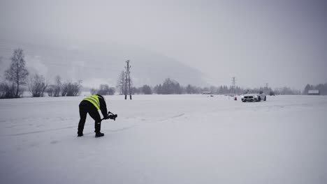 Person-with-camera-wear-green-safety-vest-at-winter-drift-competition