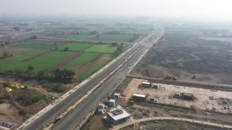 Rajkot-Atal-lake-drone-view-drone-camera-moving-forward-big-building-work-going-on-and-lots-of-vehicles-moving-on-the-road,-Rajkot-New-Race-Course,-Atal-Sarovar